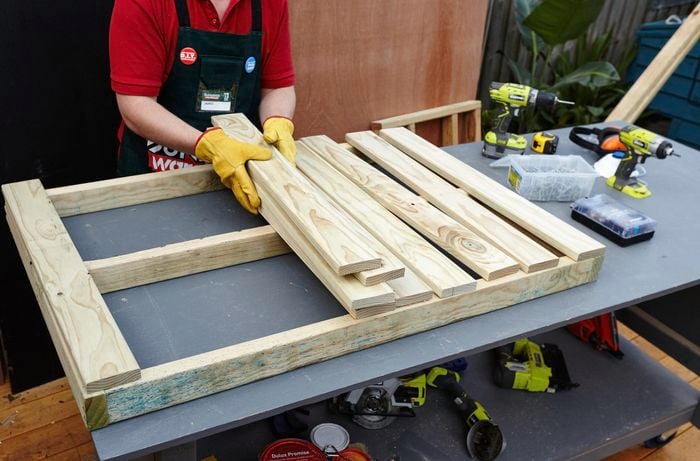 Person picking up timber slats.