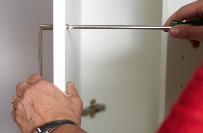 Person screwing handle to panel door.