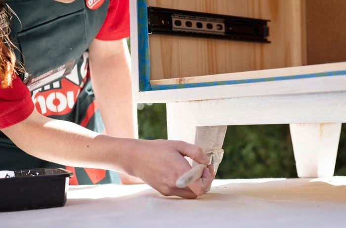 Person painting the legs of a wooden bedside table