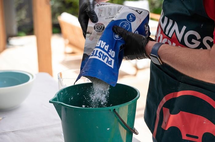 bunnings team member pouring plaster mix into a bucket