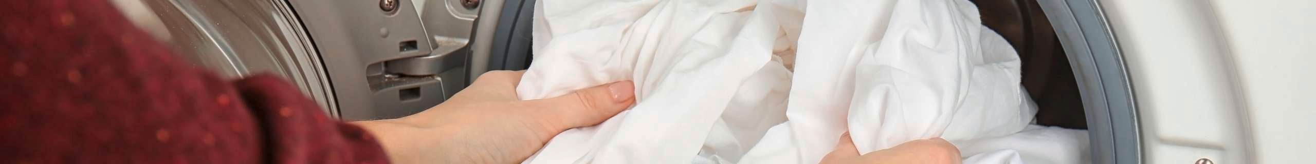 Hands pulling out clothes from the wash with OMO being used