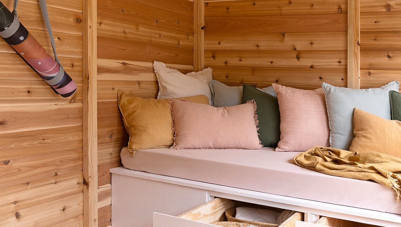 A built-in seat with open drawers in a timber line home yoga studio