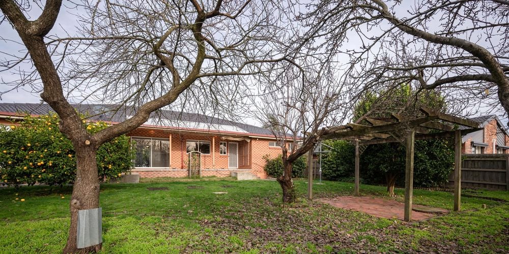 The back of a brick house with a trees in it
