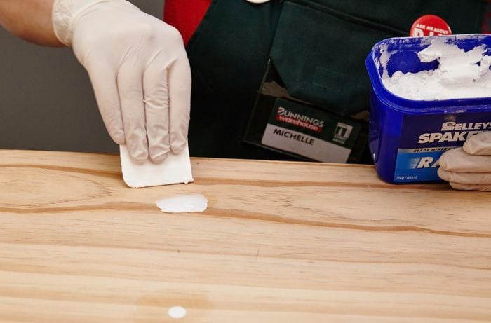 Screw holes being filled by a Bunnings team member with some gap filler