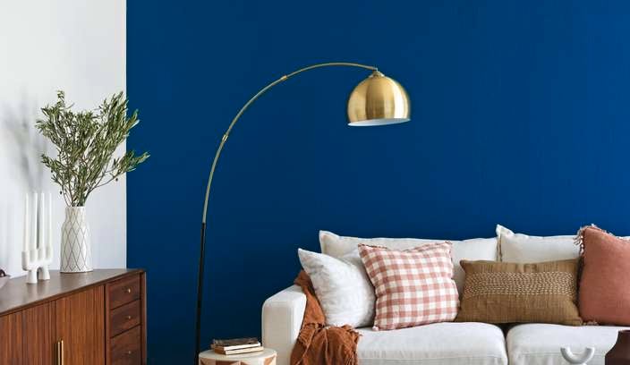 A living room with a navy blue wall, couch, buffet table and rug.