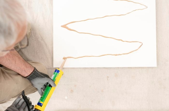 Apply construction adhesive onto the back of the panel in a zigzag pattern 