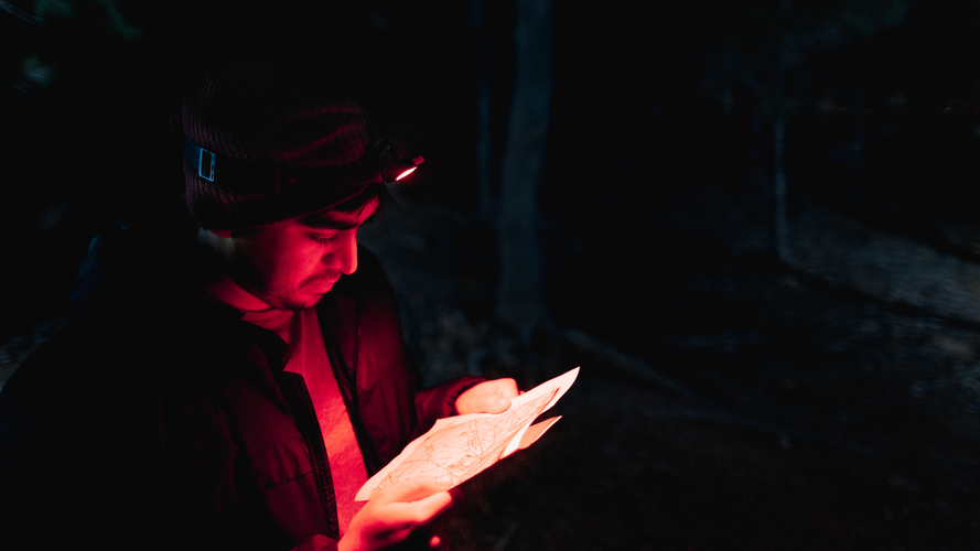 Person looking at map with red light headtorch on.