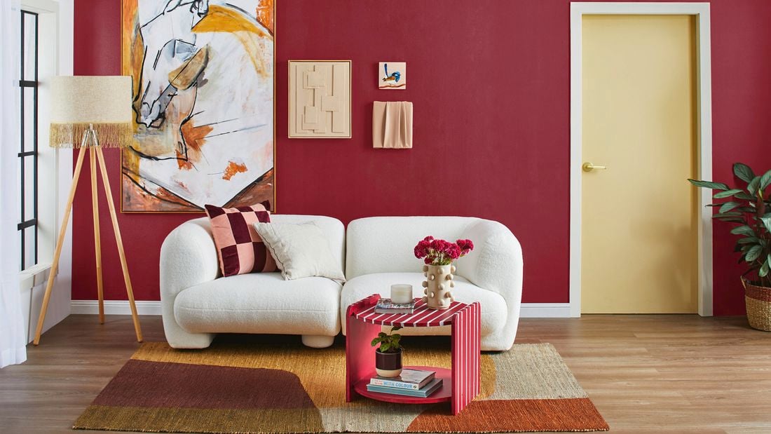Living room with red feature wall, white 3-seater lounge, cream lamp in the  courner