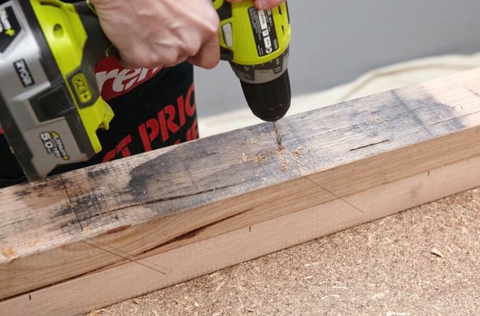 A coat rack post being drilled into as a guiding point for a bore spade to later create holes for coat hooks