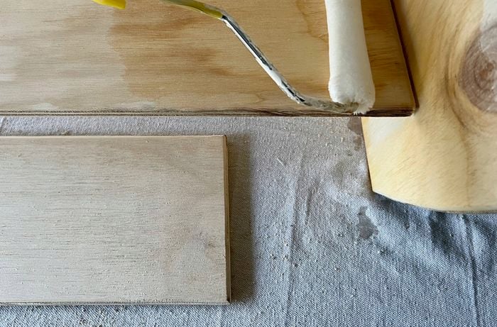Yellow mini roller applying varnish onto the inside of the wooden bookshelf