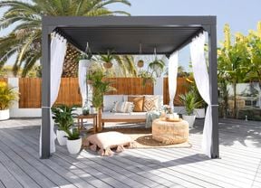 Outdoor gazebo styled with cushions, couch, hanging baskets and sheer curtains.