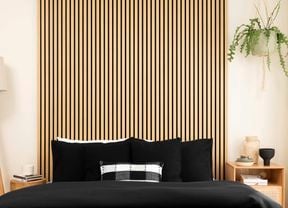 A room with floor lamp, bed and timber panels on the wall.