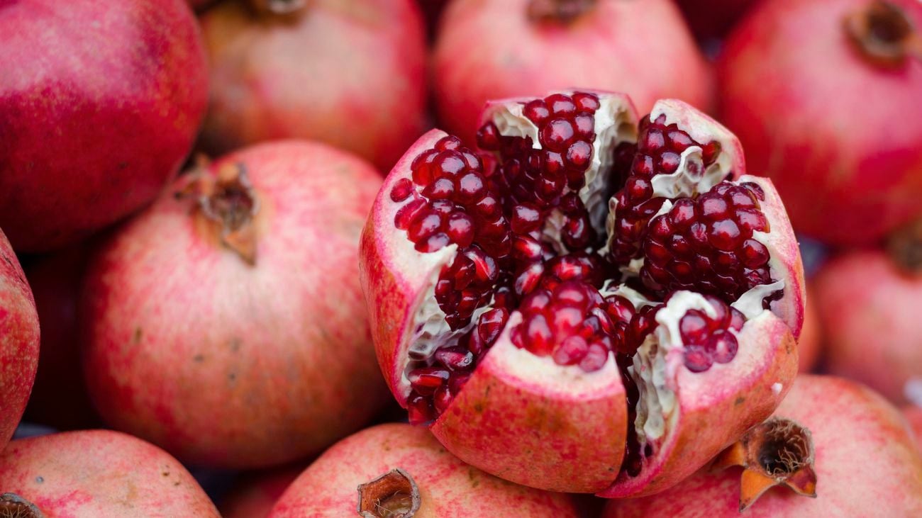 Red pomegranate fruits, one cut open to reveal seeds