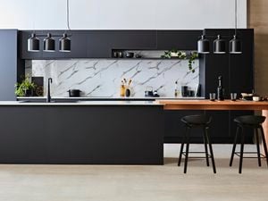 Kitchen with black benches and marble splashback.