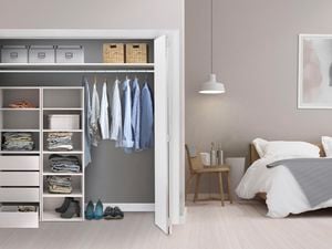 Organized built in wardrobe in bedroom with bed and chair.