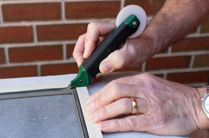 A person is carefully lifting and removing the spline using a spline roller tool.