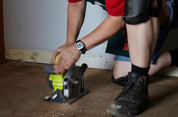 Bunnings team member using a circular saw to cut into floorboards