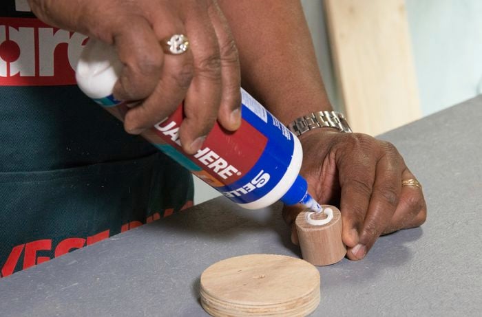 A person applying glue to the end of a dowel rod