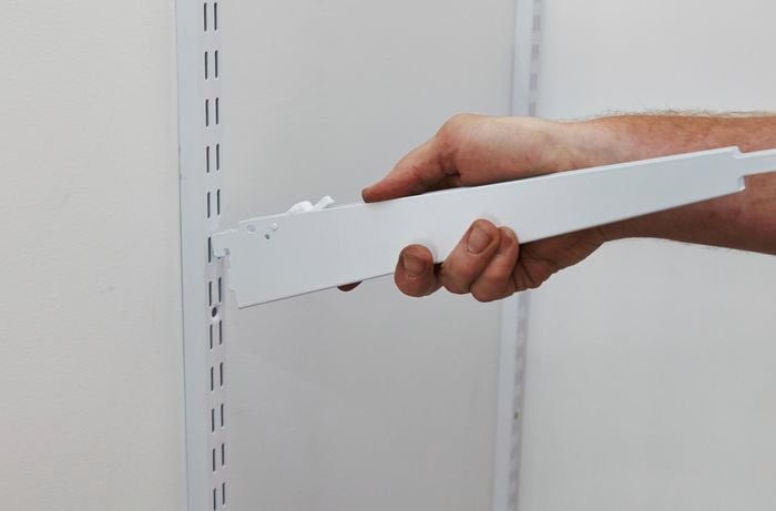 A shelf support arm being clipped into a wall mounted bracket