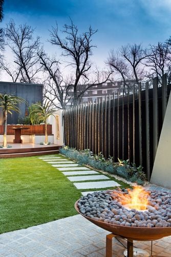 A fire pit overlooking a lawn, pavers and a deck