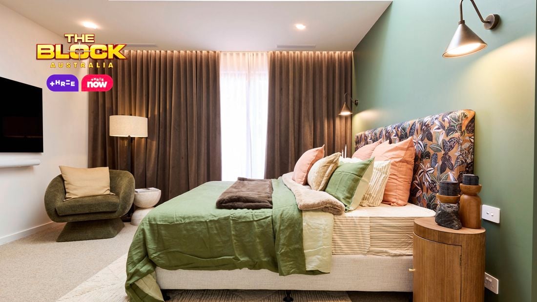 Bedroom with green feature wall, patterned headboard, and layered bedding.