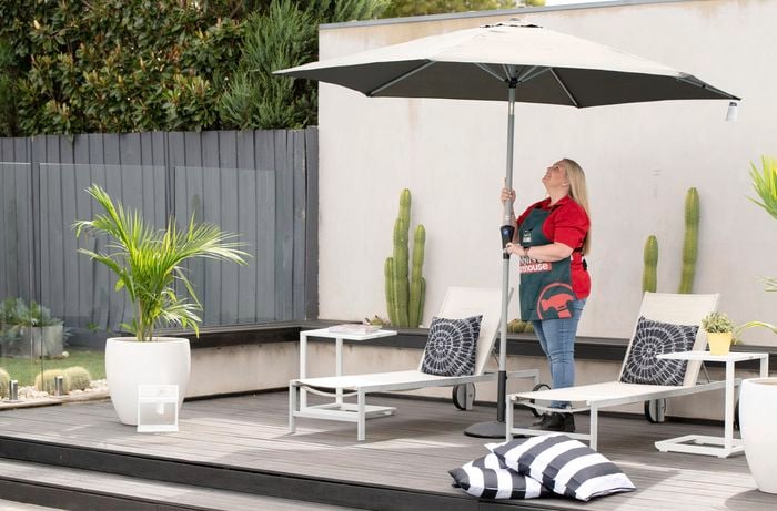 A Bunnings team member erecting an umbrella in an outdoor pool area