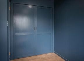 Image of a wardrobe with two doors, painted in a deep shade of navy blue, with a smooth and glossy finish.