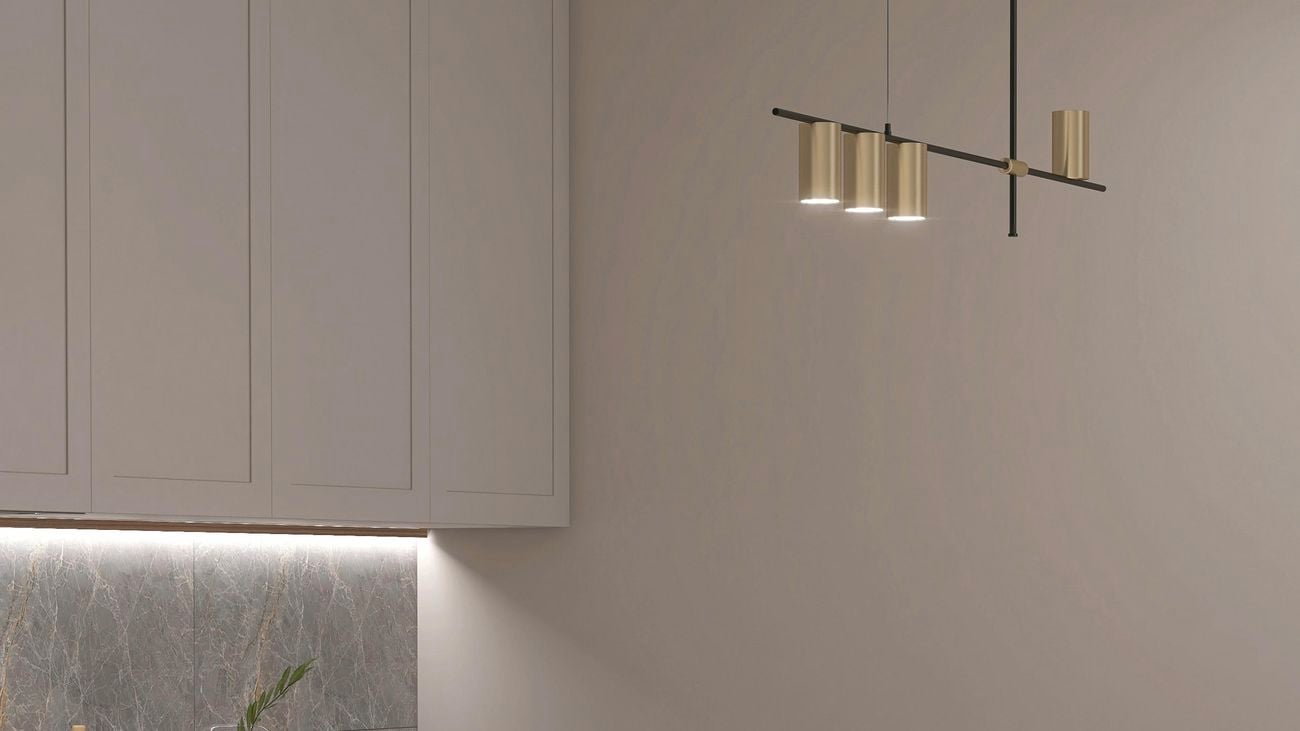 Modern white marble top dining table island, with gold, brass lights overhead.