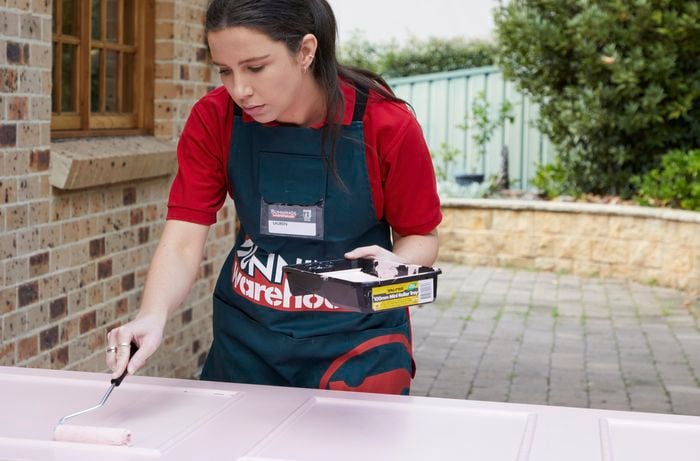 A woman painting a door pink