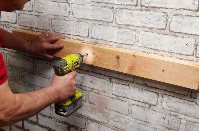 Person drilling timber into wall.