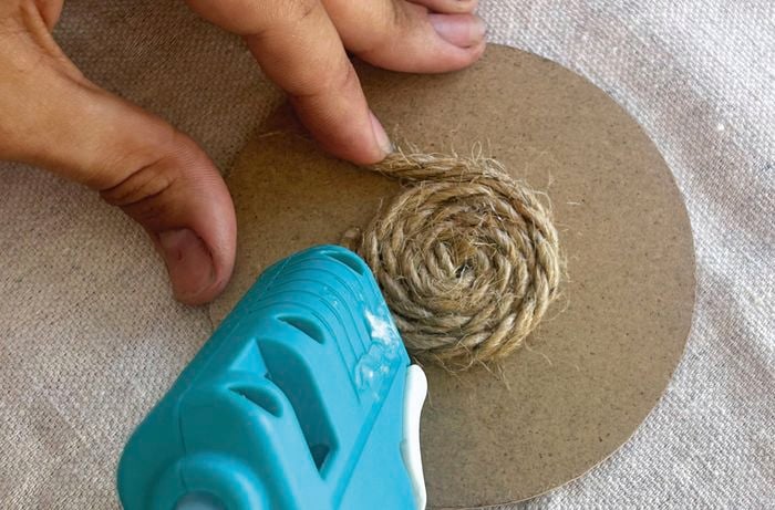 person glueing a spiral of jute 