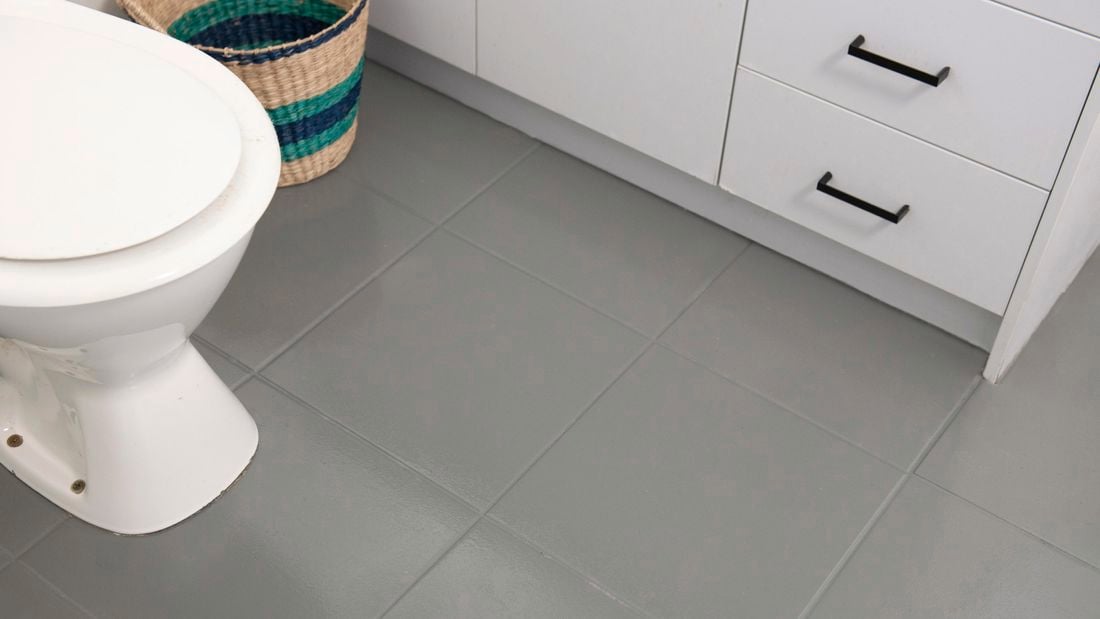 A bathroom with toilet and slate coloured floor tiles