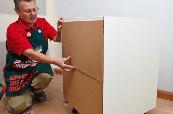 Person attaching back to cupboard