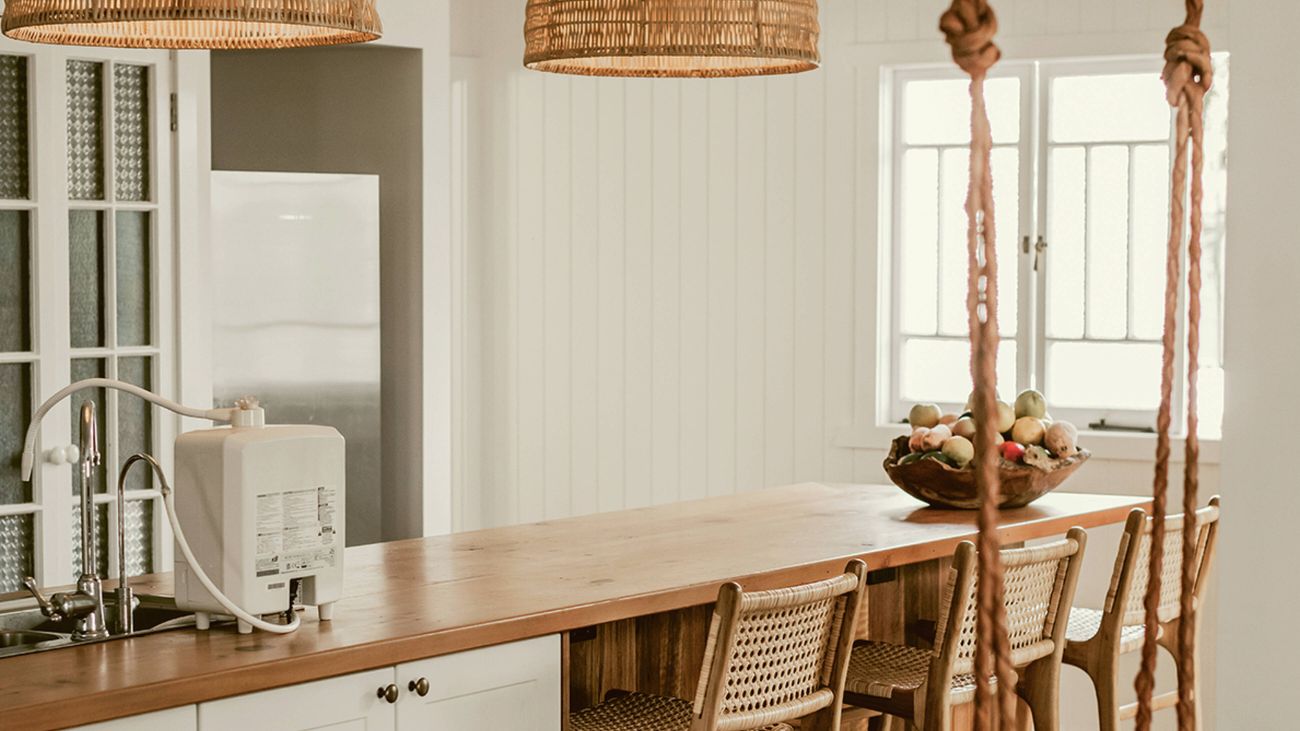 Kitchen island with wooden benchtop, bar stools, woven pendant lights and an indoor swing.