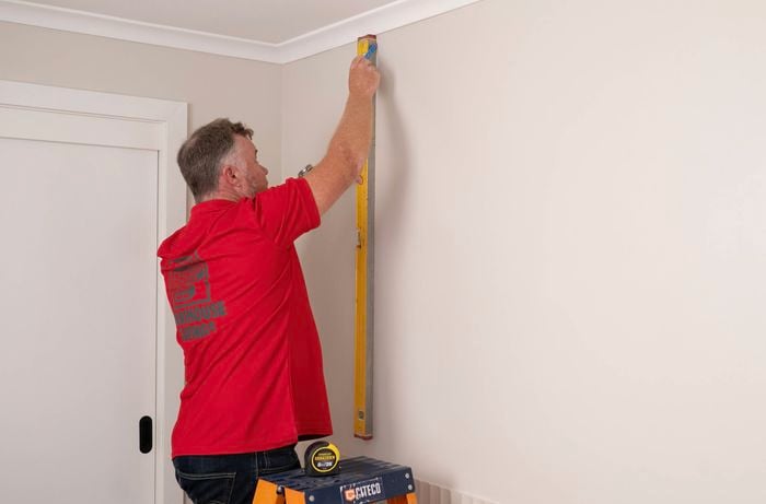 A Bunnings team member is marking sections on the wall.