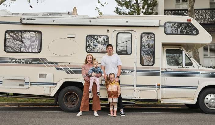 Josh, Jenna and their two children standing in front of an old campervan.