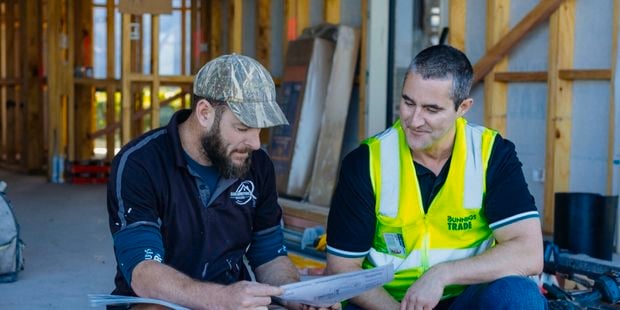 trade manager chatting with trade customer, sitting on a job site looking at plans