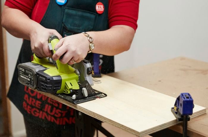 A person cutting a sheet of plywood using a circular saw