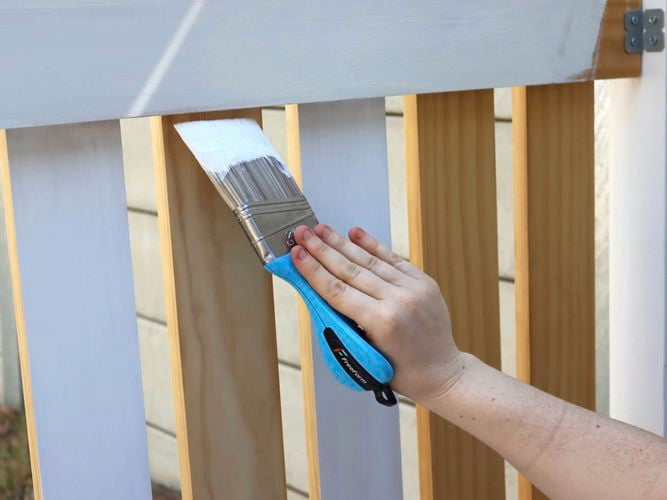 A person painting a gate.