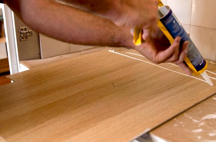 A person applying adhesive to MDF board.