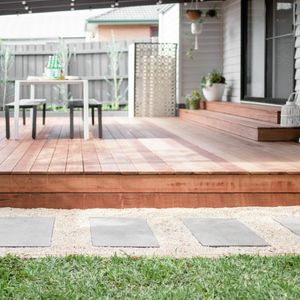 Close up of a finished stepping stone pathway beside a deck in a backyard.