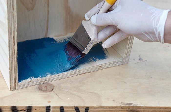 Person painting timber box with blue paint
