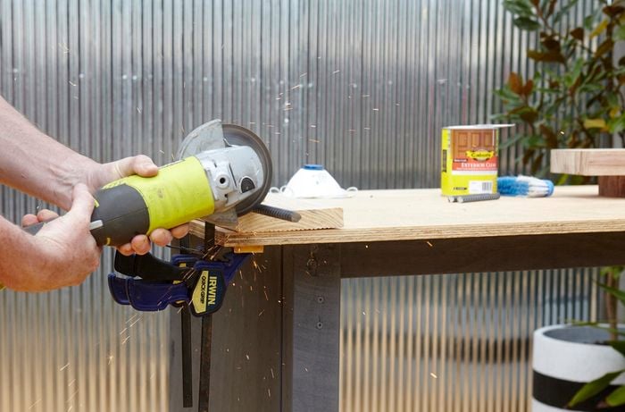Person cutting bit of timber with handheld saw.