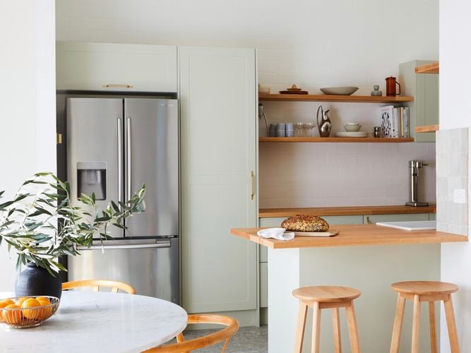 A modern kitchen with timber shelves, stools and benchtop.