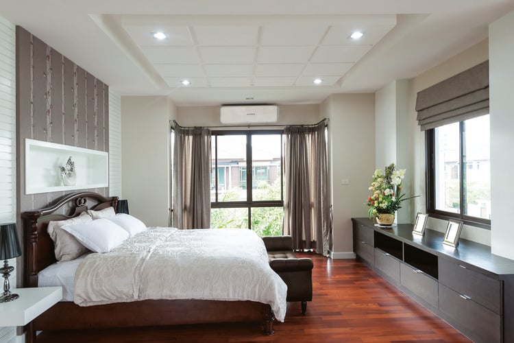 Bedroom with red timber flooring and queen sized bed with timber bedhead