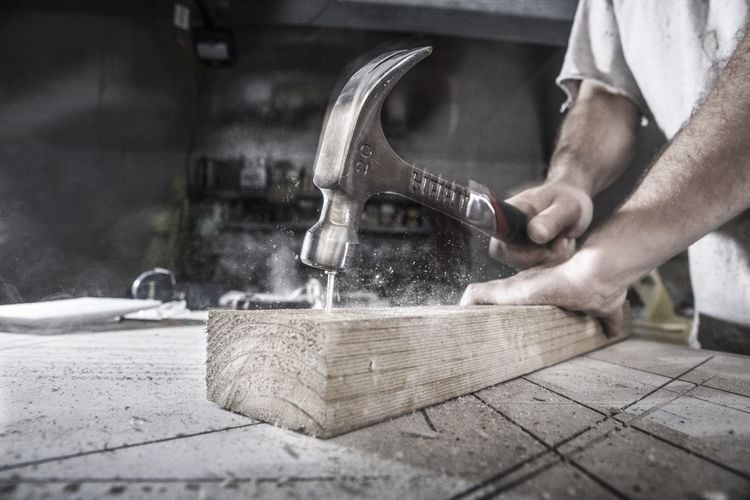 A hammer driving a nail into a piece of timber