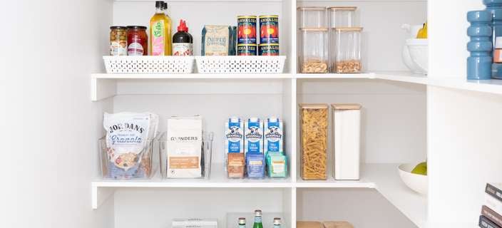 Kitchen pantry with white shelving, neatly displayed with white storage containers