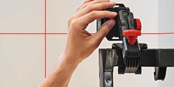 A person's hand pressing a button on the Bosch Levelling Quigo.
