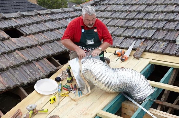 A Mylar tube being fitted to a sheet of tin flashing by a Bunnings team member on a roof