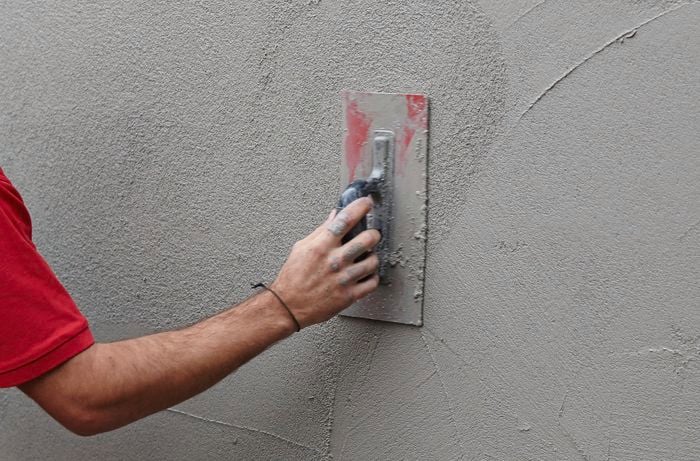 A trowel being used to smooth render on a wall
